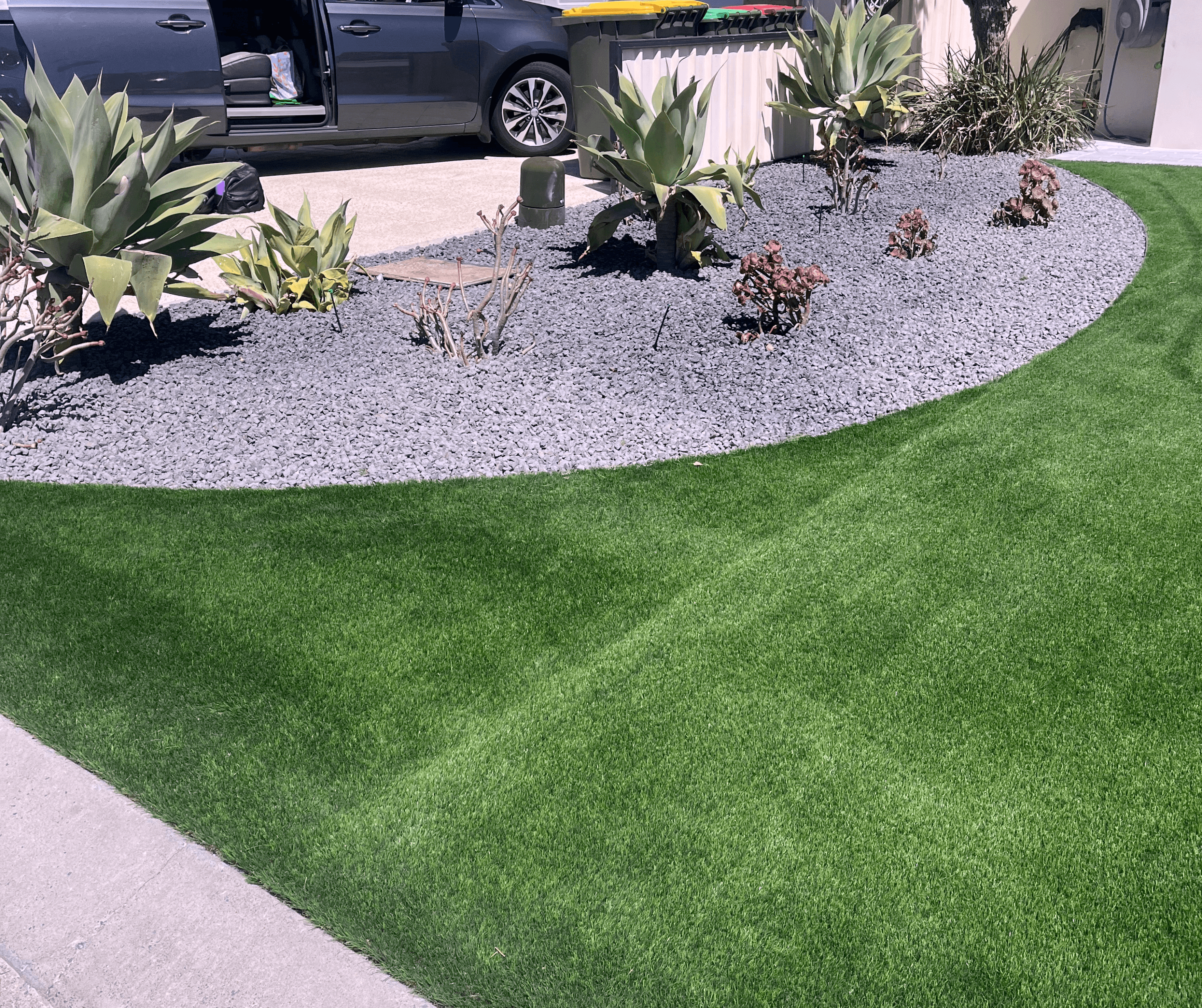Artificial lawn curving around a gravel garden bed with agaves